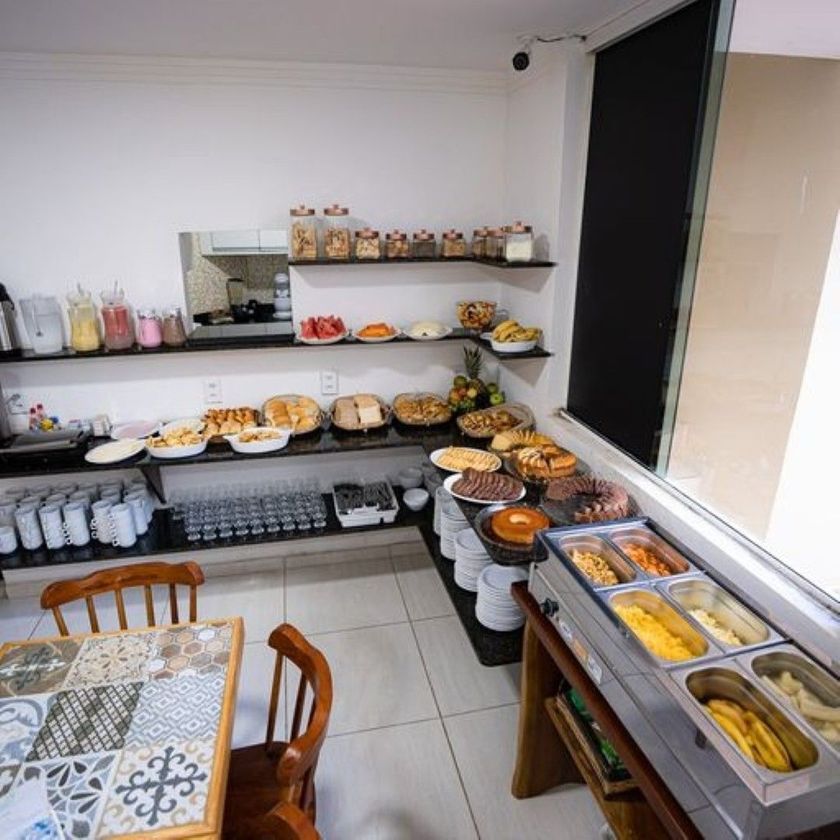 Sala de jantar elegante de restaurante com mesas postas, iluminação aconchegante e grandes janelas com persianas.