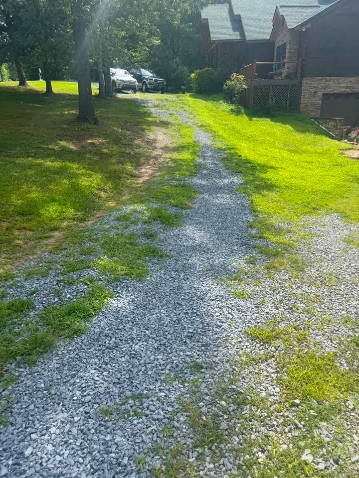 Gravel driveway between green lawns and houses in bright sunlight