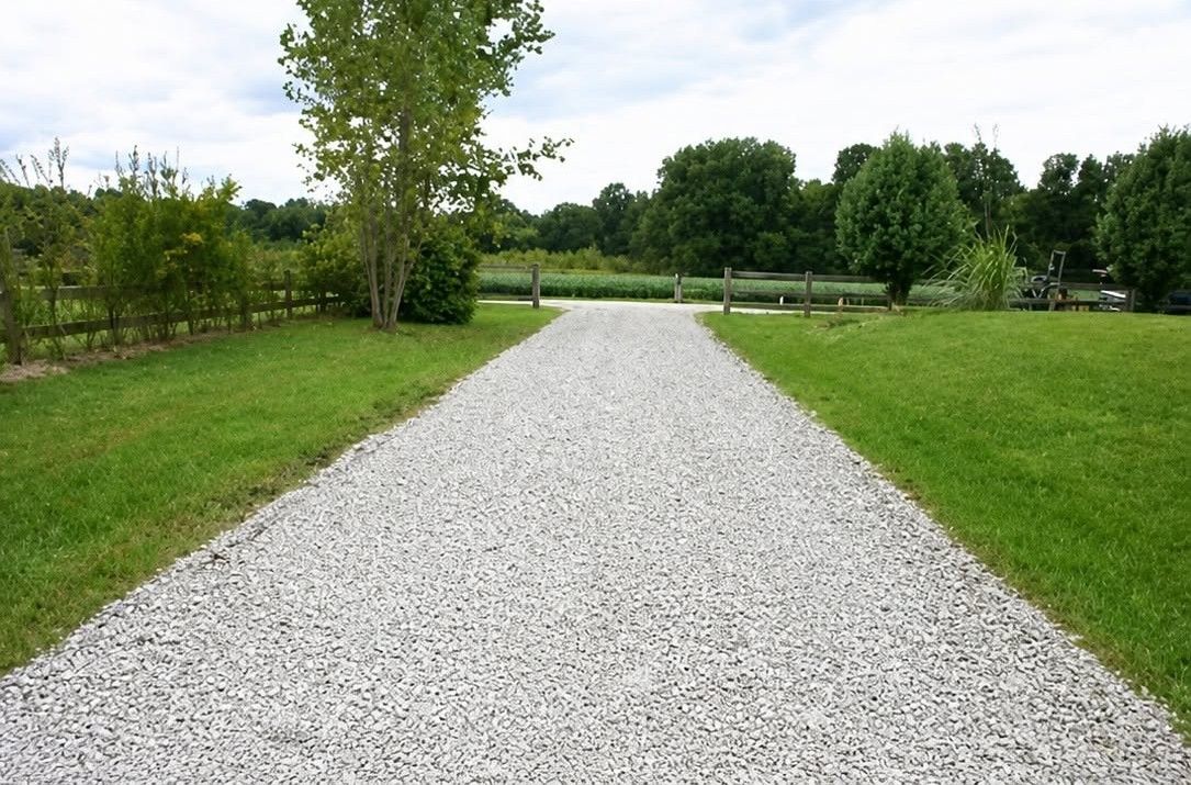 Gravel path through a green park with trees and lawn on both sides