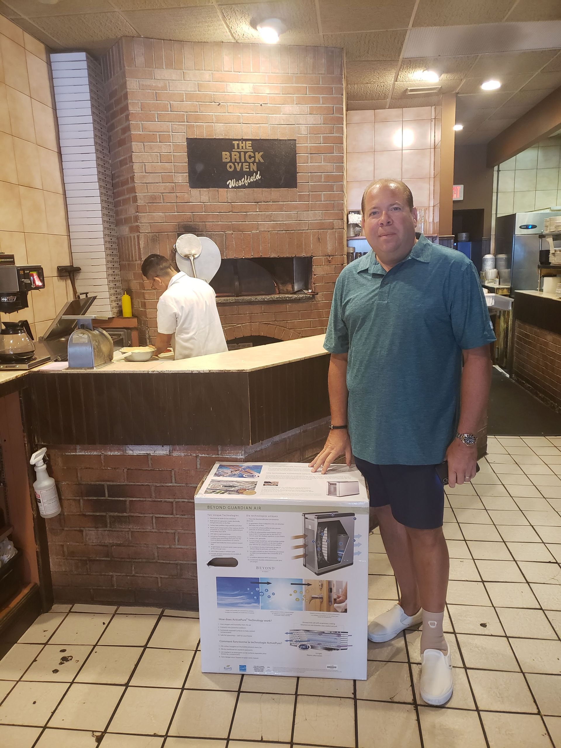 Man standing beside a box in a restaurant lobby near a counter and staff area