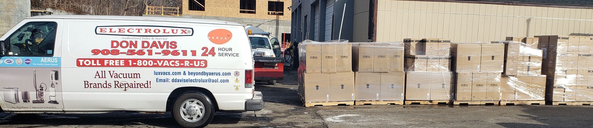 White delivery van parked beside stacked cardboard boxes in an industrial yard