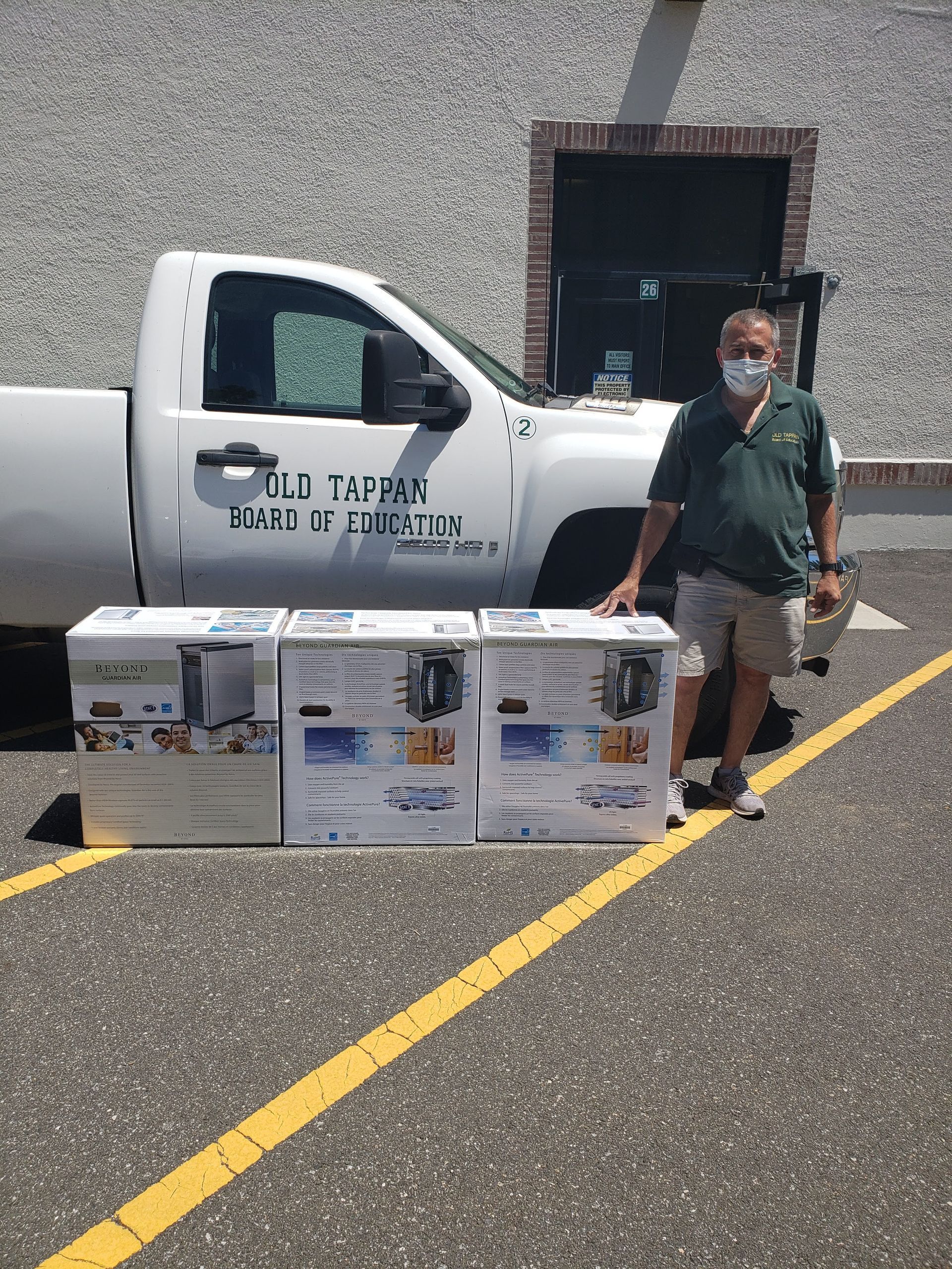 Worker beside white utility truck with boxes of bottled water in a parking lot