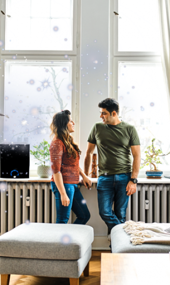 Two people standing and talking by a bright window in a cozy living room