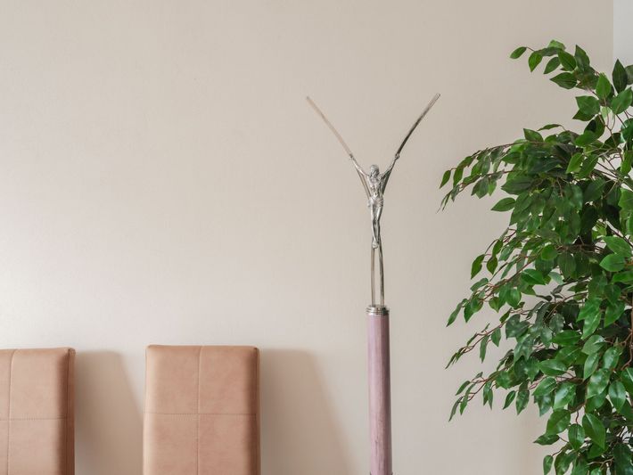 Angolo minimalista con due sedie beige, una lampada da terra rosa alta e una pianta verde rigogliosa.