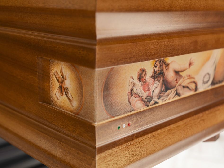 Urna in legno con scena biblica dipinta e piccole luci indicatrici rosse, verdi e bianche.