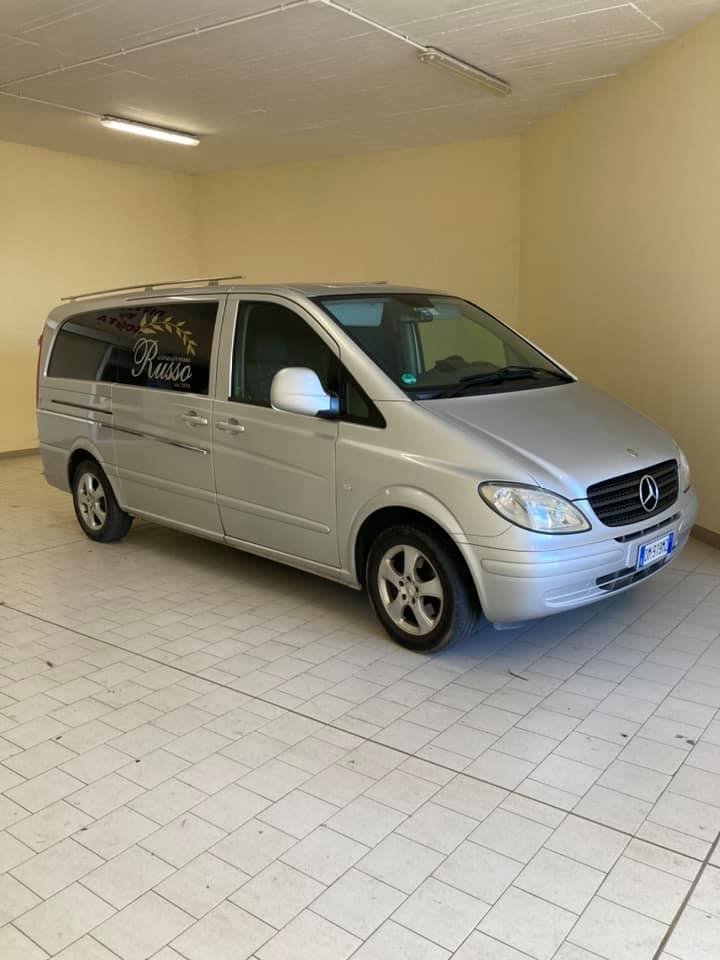 Furgone Mercedes argentato parcheggiato all'interno, su un pavimento piastrellato, in un garage o in uno showroom.