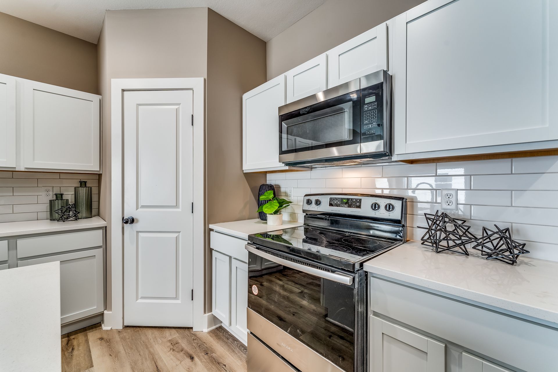 A kitchen with white cabinets , stainless steel appliances , a stove and microwave.