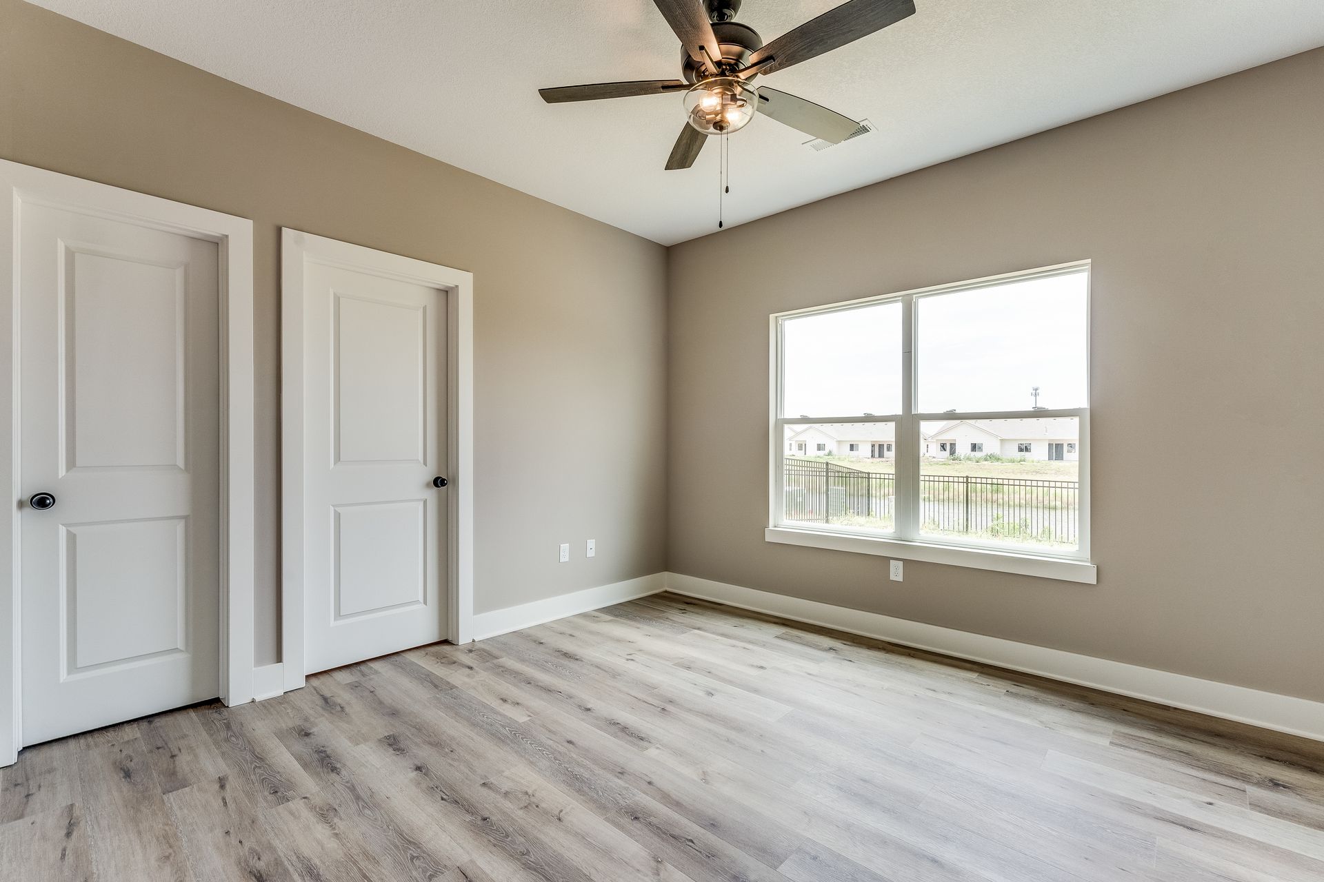 An empty bedroom with hardwood floors and a ceiling fan.