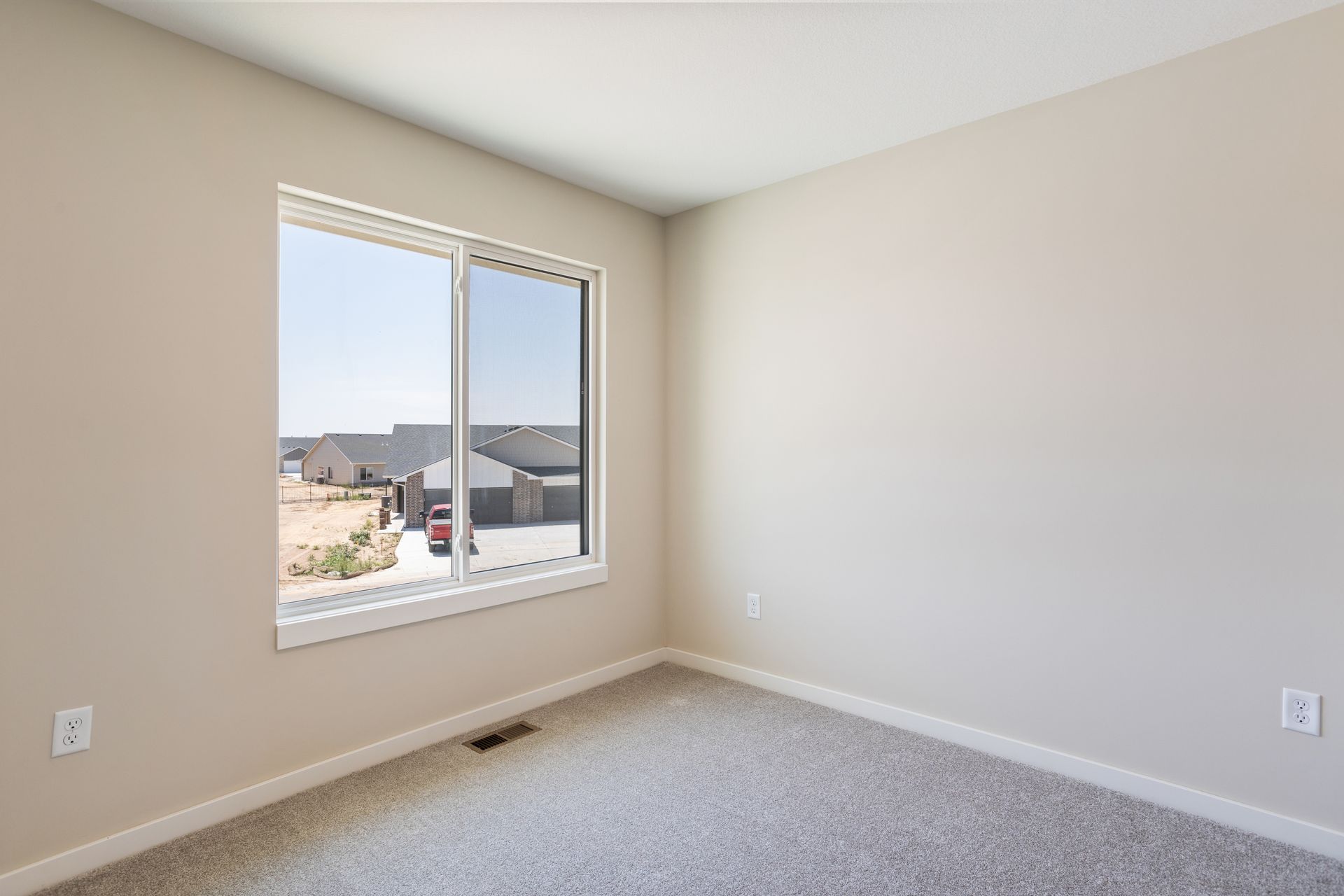 An empty bedroom with a large window and carpet.