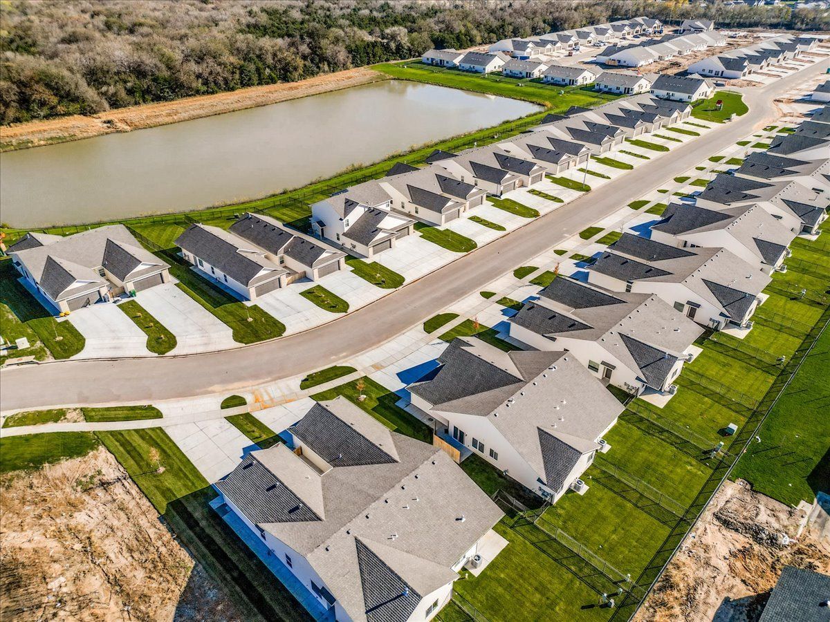 An aerial view of a residential neighborhood with lots of houses and a pond.