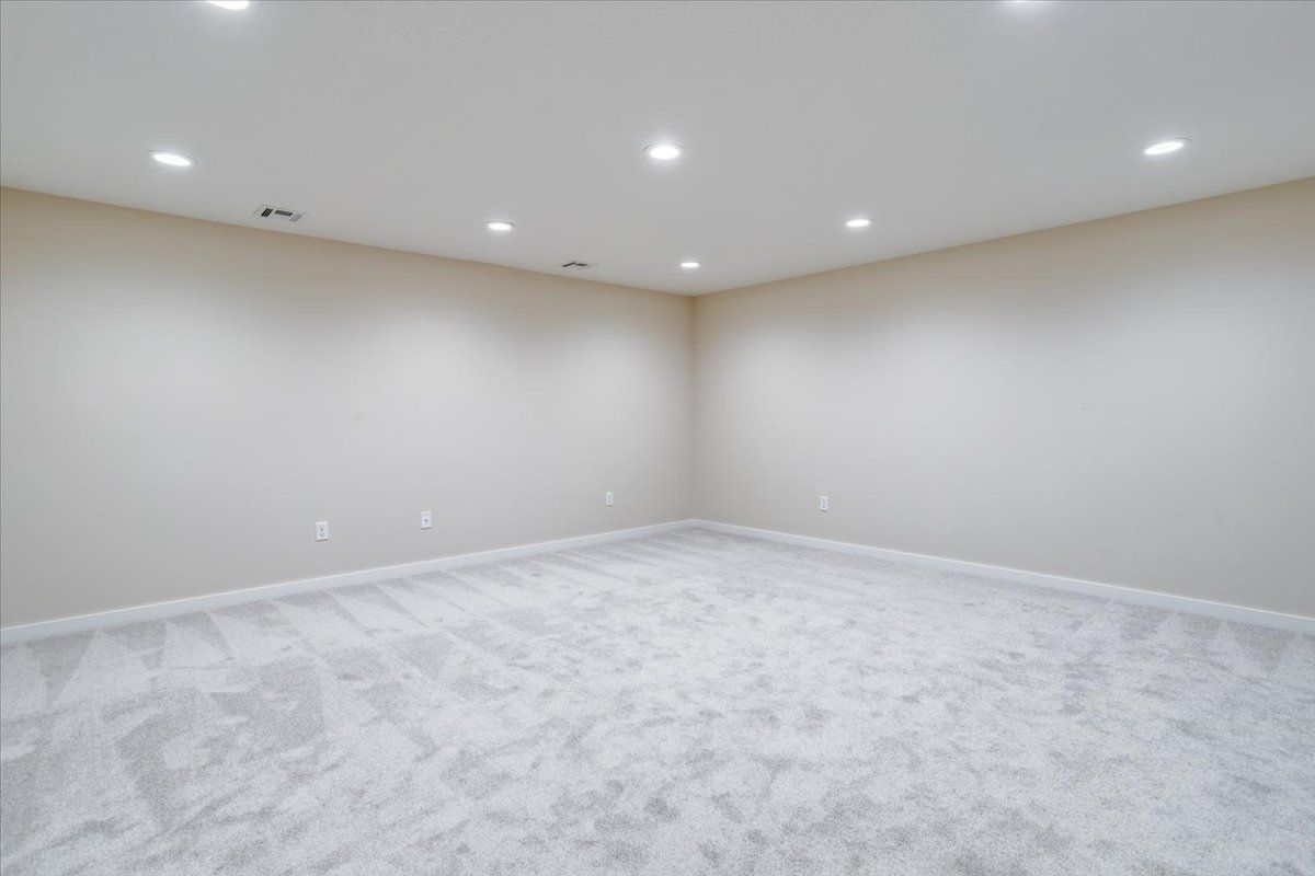 An empty basement with a carpeted floor and white walls.