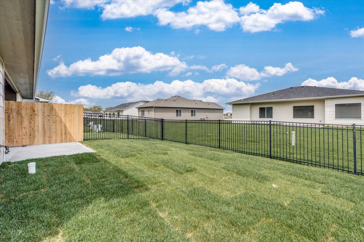 A backyard with a fence and a lush green lawn.