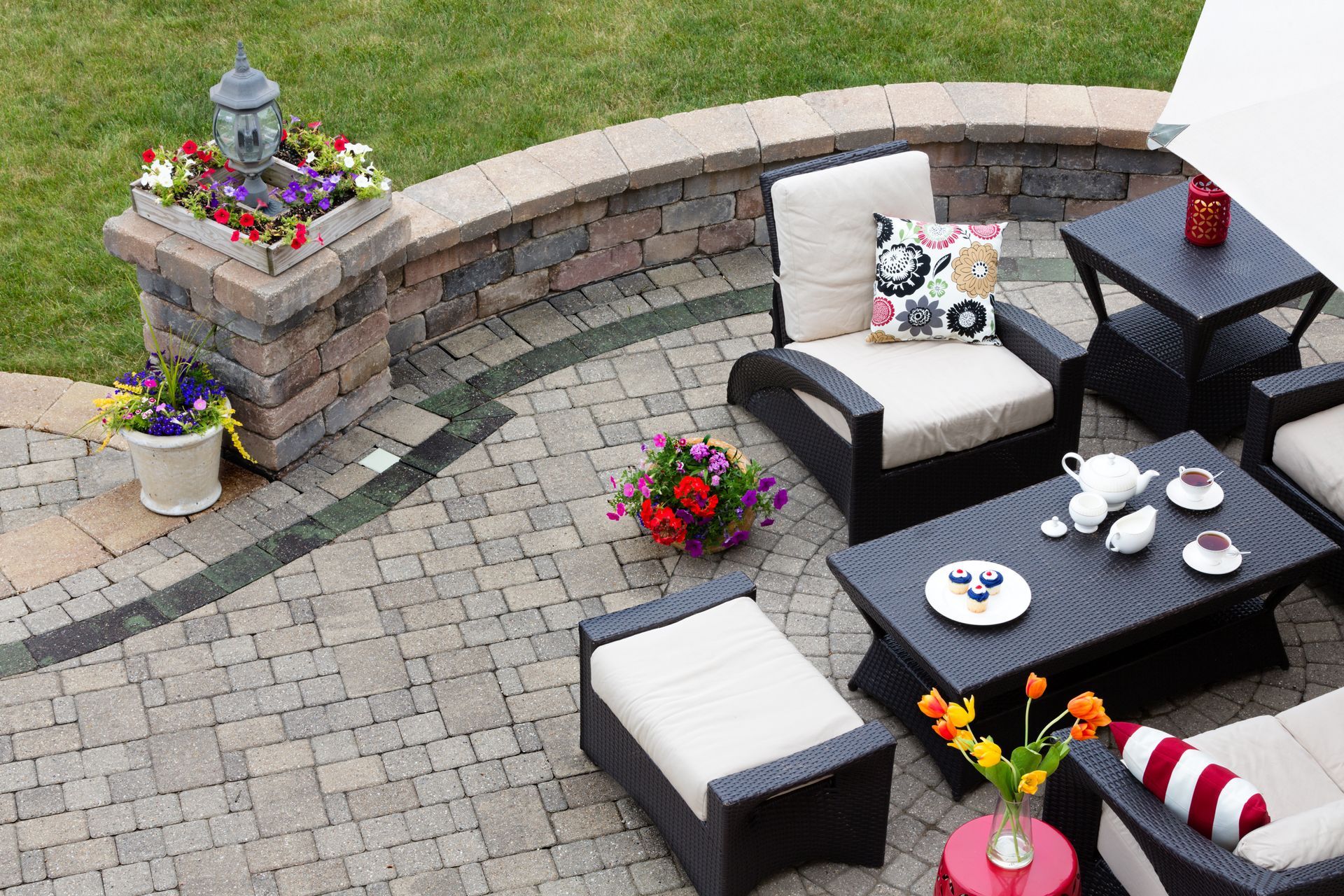 Patio with outdoor furniture, stone walls, flowers, and a brick pillar with a lantern.