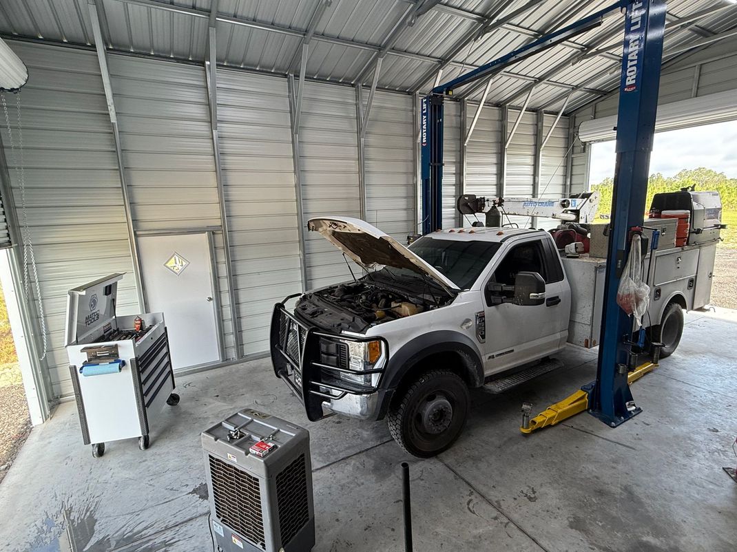 White service truck in a garage with its hood open, near a lift. | Cypress Ridge Automotive