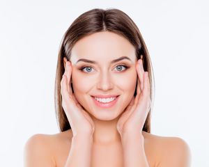 A woman is smiling and touching her face with her hands. A woman is smiling and touching her face with her hands.