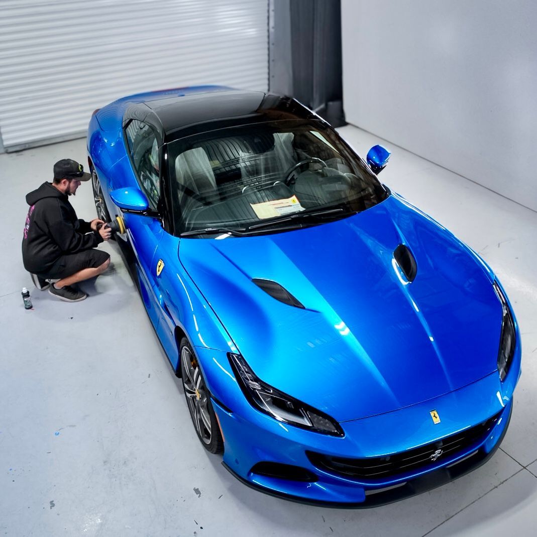 A man is kneeling next to a blue sports car