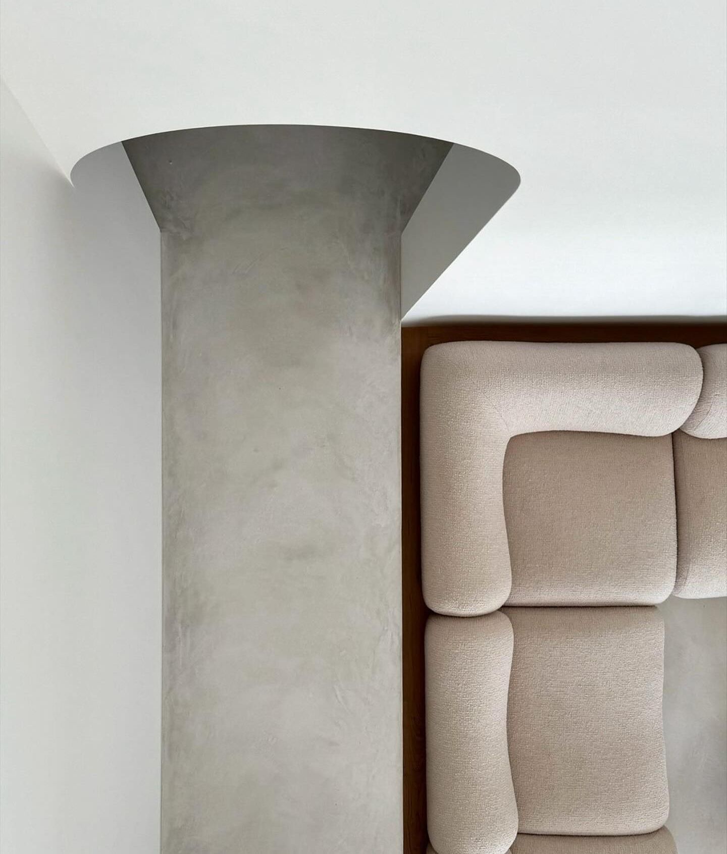 A couch is sitting next to a concrete column in a living room.