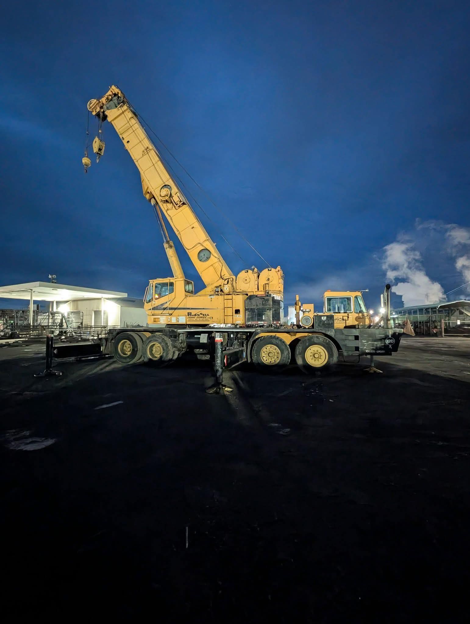 Yellow crane at dusk. Dark ground, blue sky.