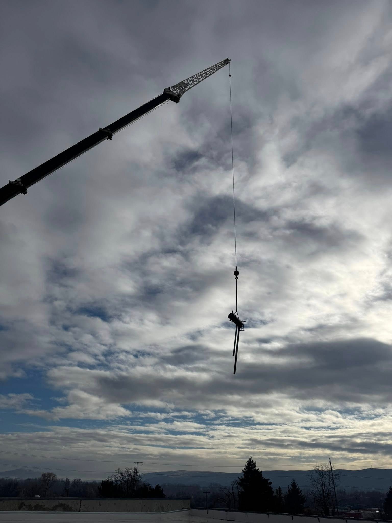 Crane lifting debris against a cloudy sky.