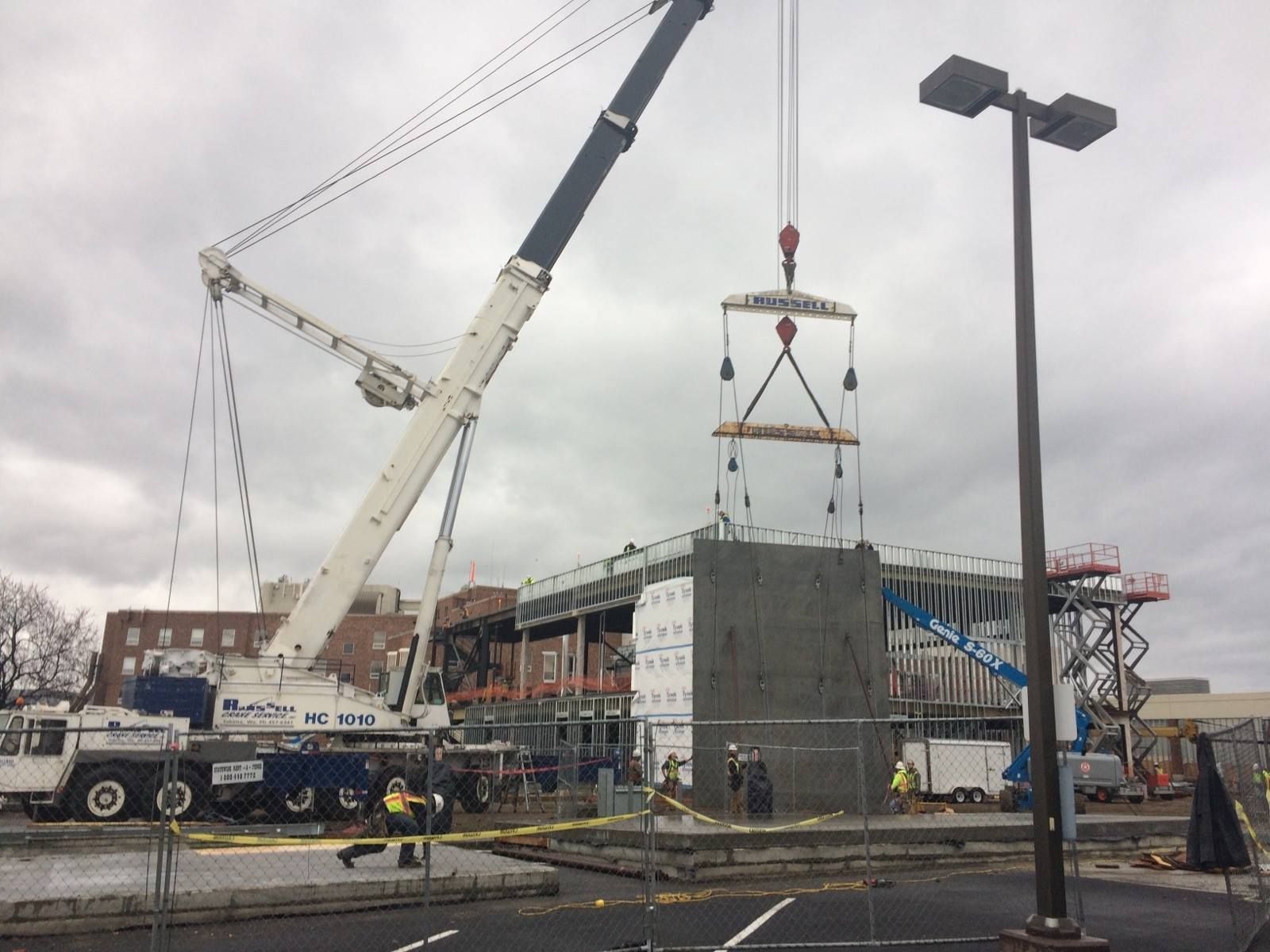 Construction site with a crane lifting a concrete wall section.