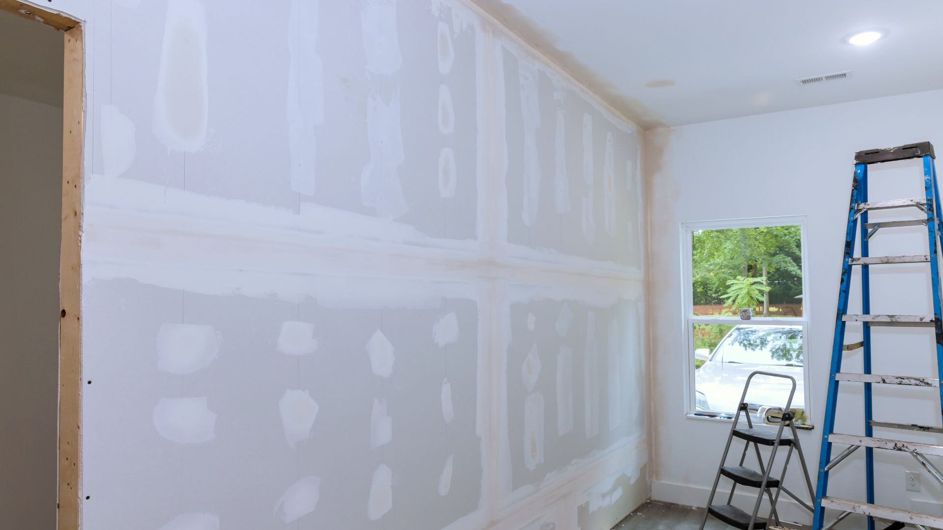 A room with drywall and a ladder in it.