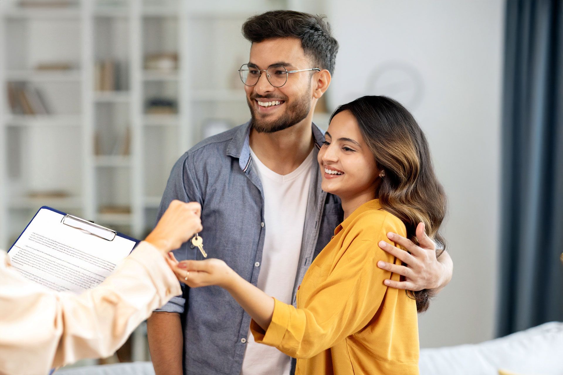 Smiling couple receiving house keys from a realtor in a bright living room