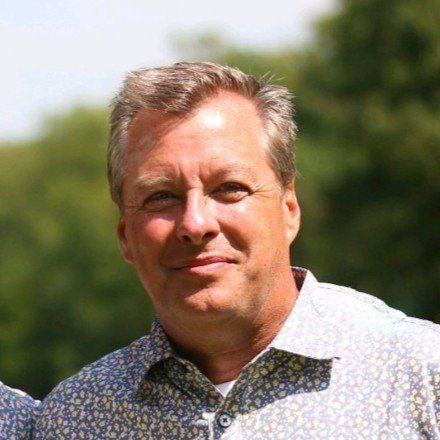 A man in a blue shirt is smiling for the camera.