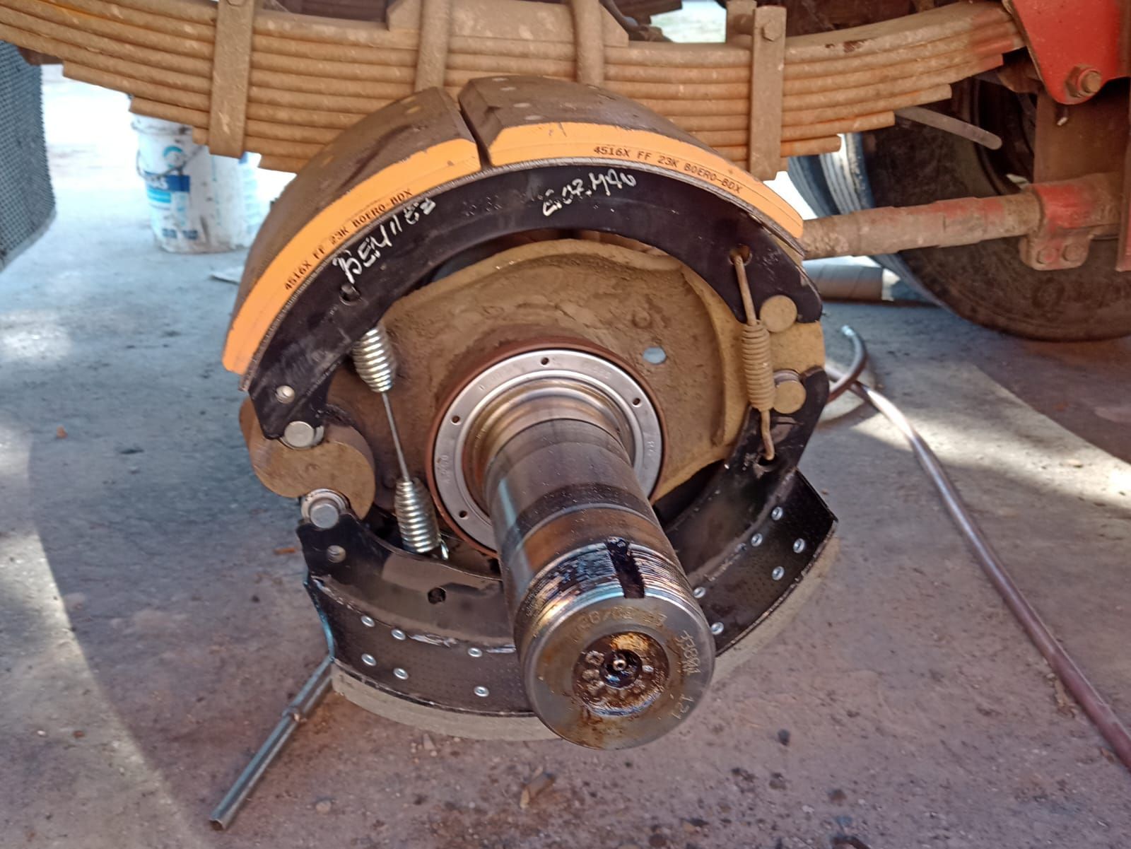 Conjunto de cubo de rueda trasera y tambor de freno en un vehículo, con el eje expuesto en un taller.