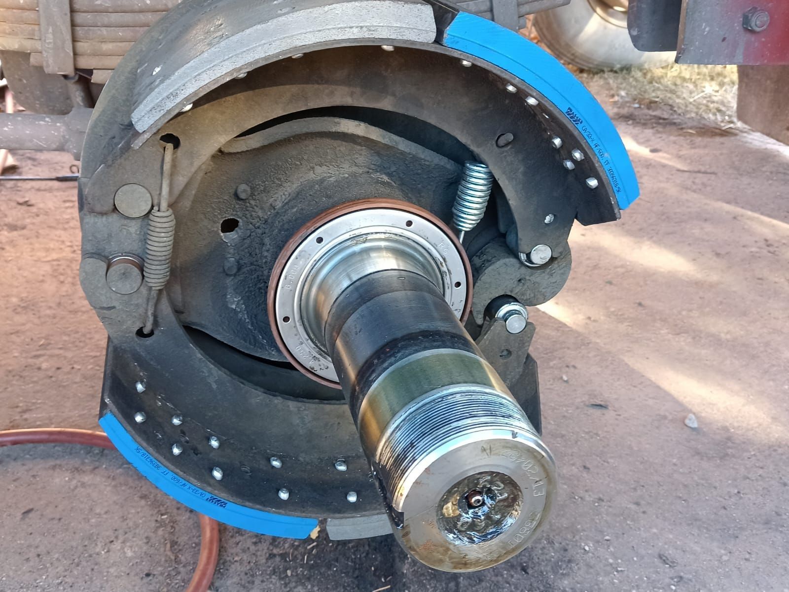 Primer plano de un conjunto de eje metálico con anillos protectores azules en un entorno de taller.