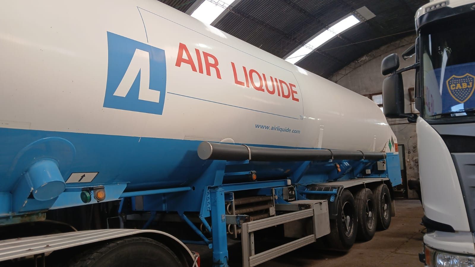 Camión cisterna de Air Liquide en un almacén, de color blanco y azul con logotipo rojo.