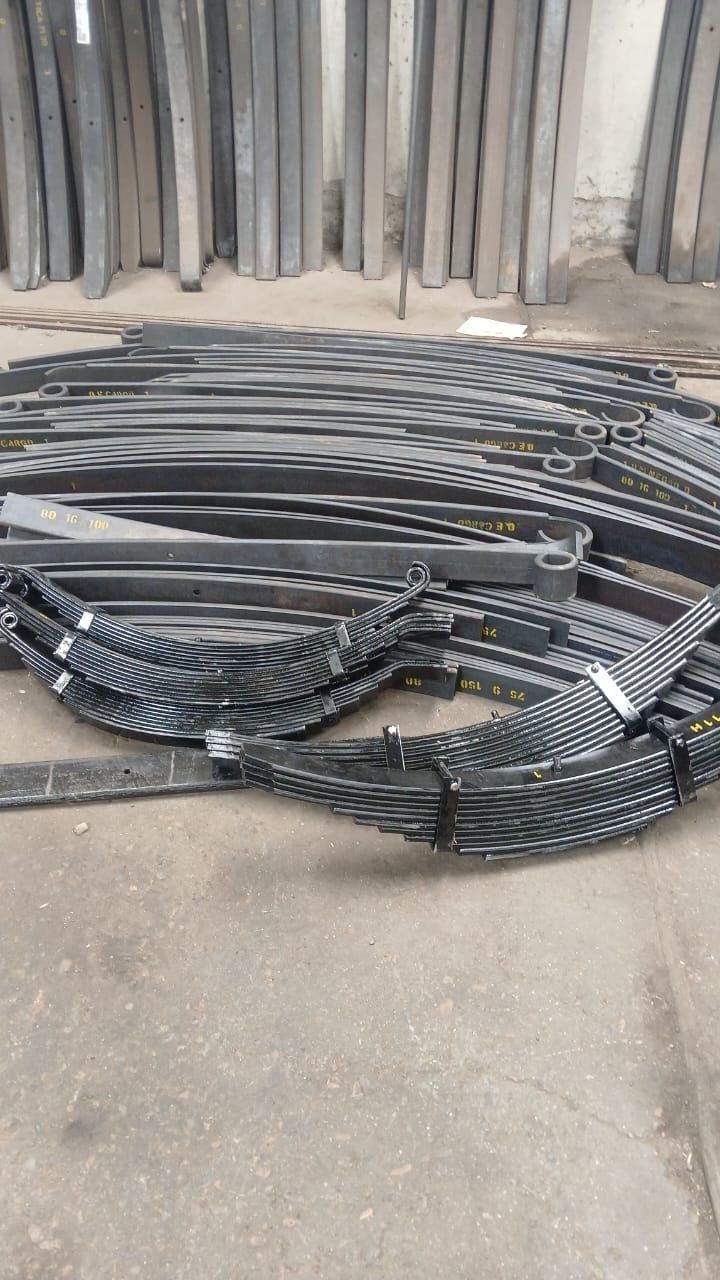 Cadena transportadora de metal negro enrollada y apilada sobre un suelo de hormigón en un taller industrial.