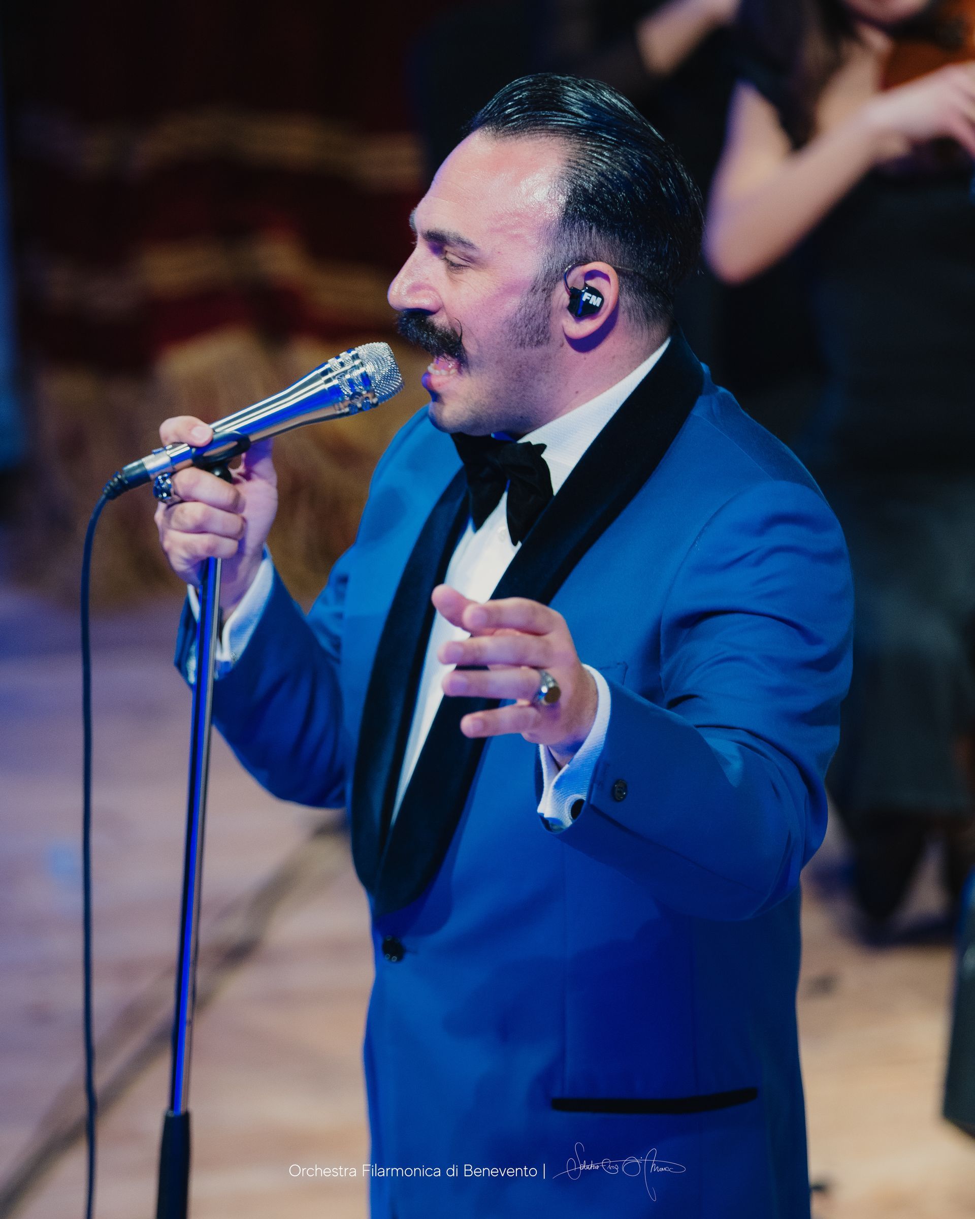 Un uomo vestito di blu canta al microfono