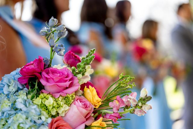 Colorful bouquet of flowers in the foreground with blurred people standing outdoors in the background