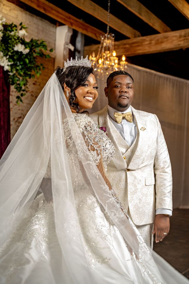 Bride and groom in ivory wedding attire smiling in a rustic indoor venue