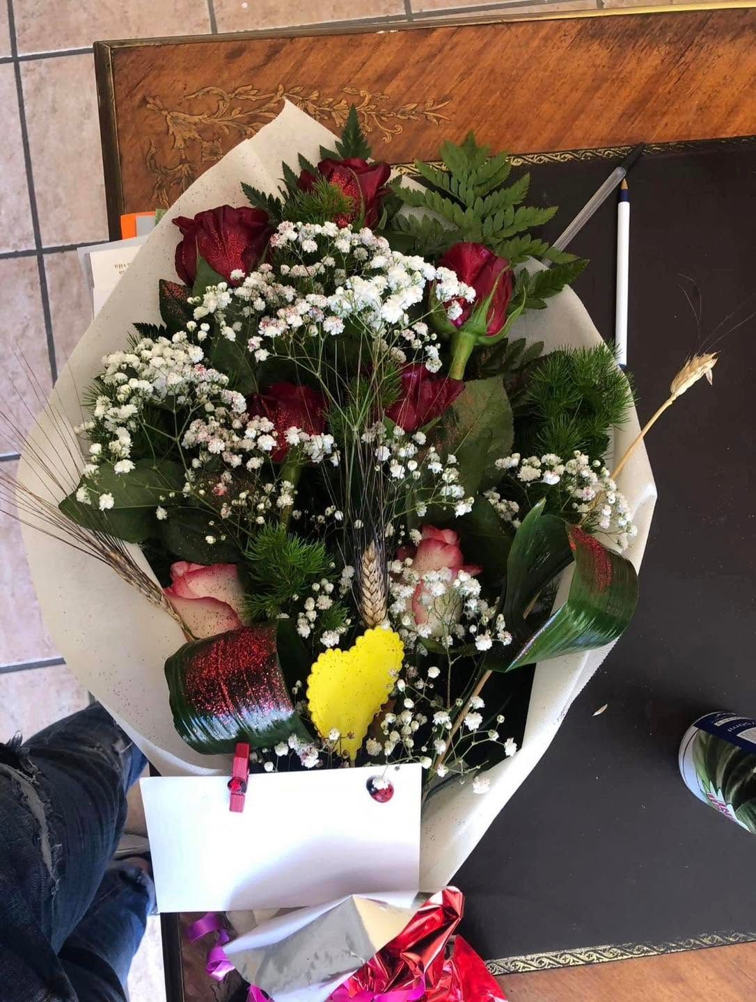 Bouquet di rose rosse e gypsophila in carta bianca su un tavolo nero.