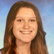 Woman with long brown hair smiles, facing the camera.