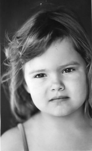 A young child with light skin and short hair looks at the viewer with a neutral expression.