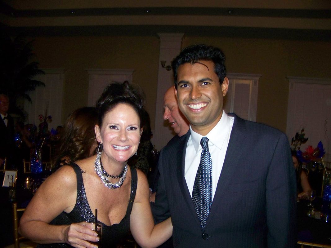 Woman and man smiling at a formal event, woman in black dress, man in a suit.