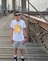 Person in sunglasses on Brooklyn Bridge, wearing white t-shirt and grey shorts.