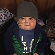 Child wearing beanie and jacket with nasal cannula.