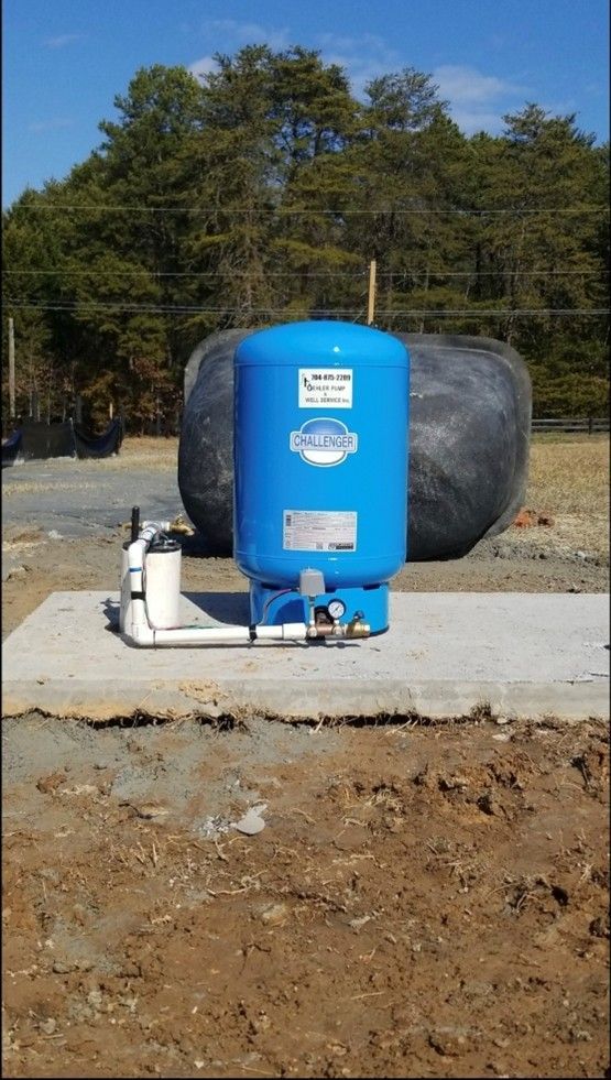 A vertical, full shot shows a bright blue Challenger water pressure tank sitting on a rectangular concrete pad A vertical, full shot shows a bright blue Challenger water pressure tank sitting on a rectangular concrete pad