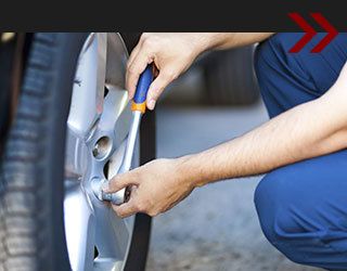 Person using a wrench to tighten a lug nut on a car's wheel.