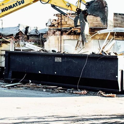 A yellow komatsu excavator is demolishing a building