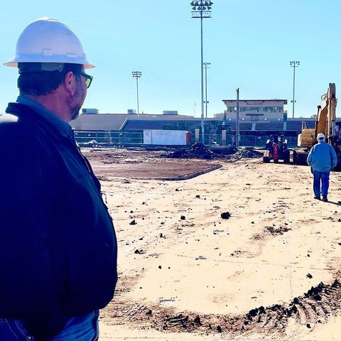 A man wearing a hard hat looks at a construction site