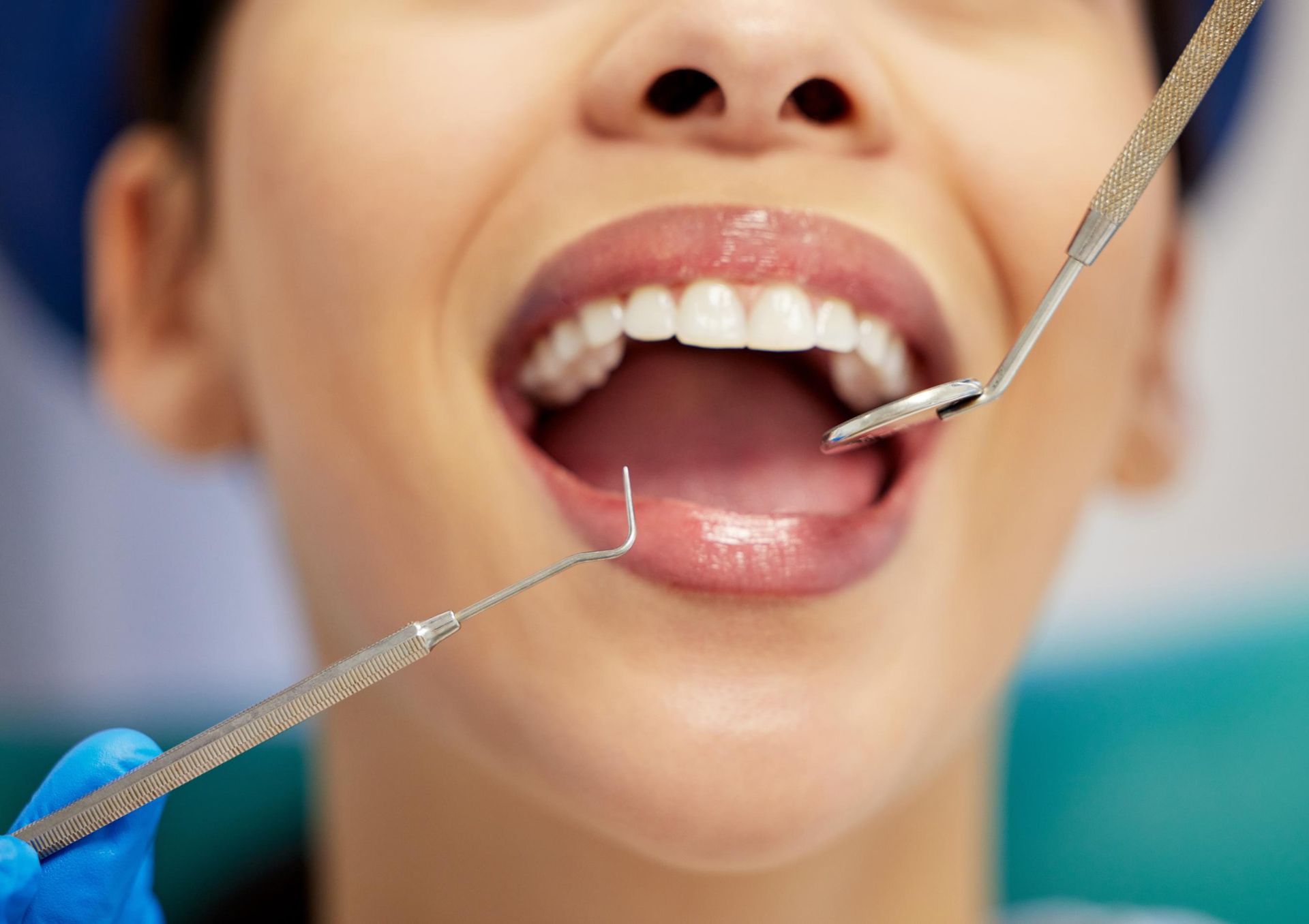 A dentist uses a mirror and a dental explorer to examine a patient's teeth.