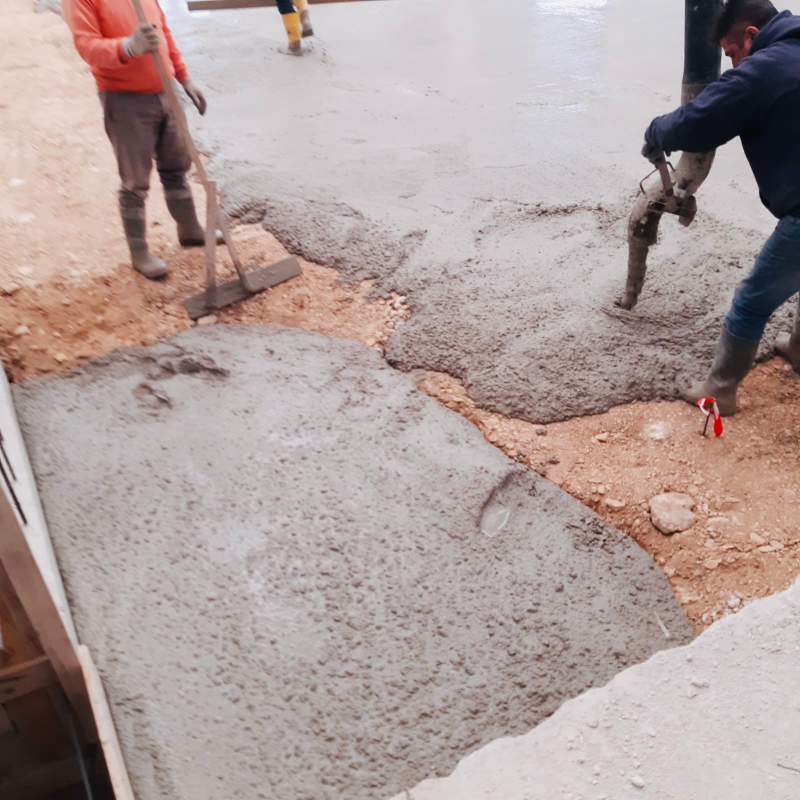 Operai che versano e lisciano il calcestruzzo in un cantiere edile.