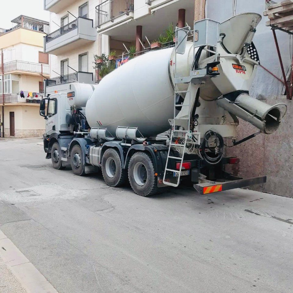 Autobetoniera parcheggiata in una strada stretta accanto a un edificio.
