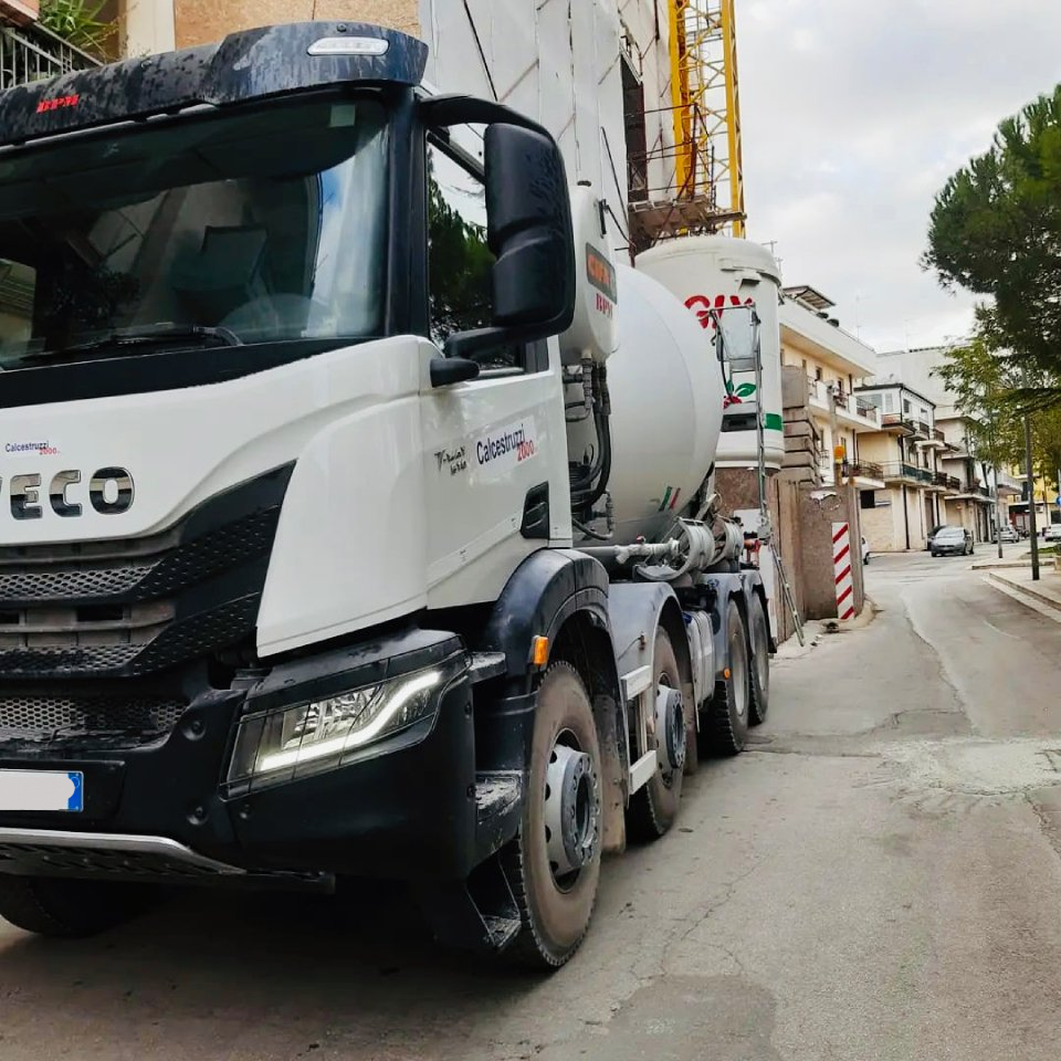 Un camion di cemento bianco parcheggiato su una strada vicino a un edificio in costruzione.