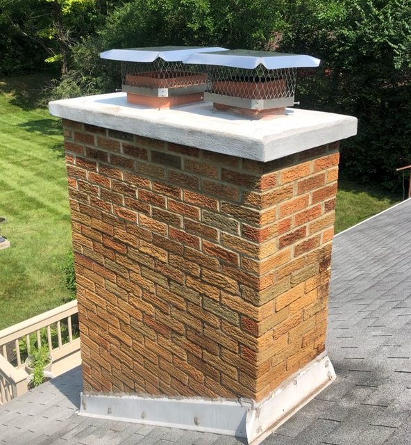 A brick chimney is sitting on top of a roof.