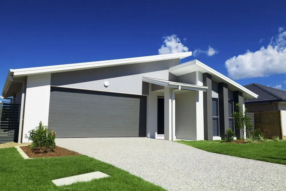 A White House With A Gray Garage Door And A Driveway — Anytime Conveyancing In Gloucester, NSW